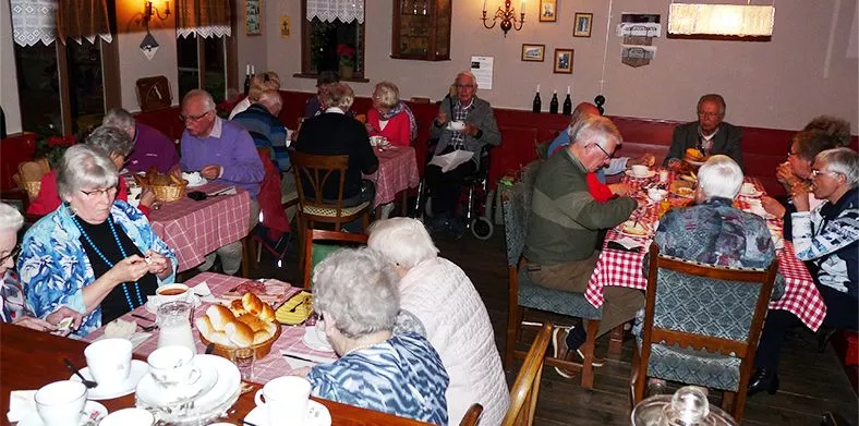 Een seniorengroep geniet van een heerlijke broodtafel lunch in een bruincafé van een museum over de Tweede Wereldoorlog
