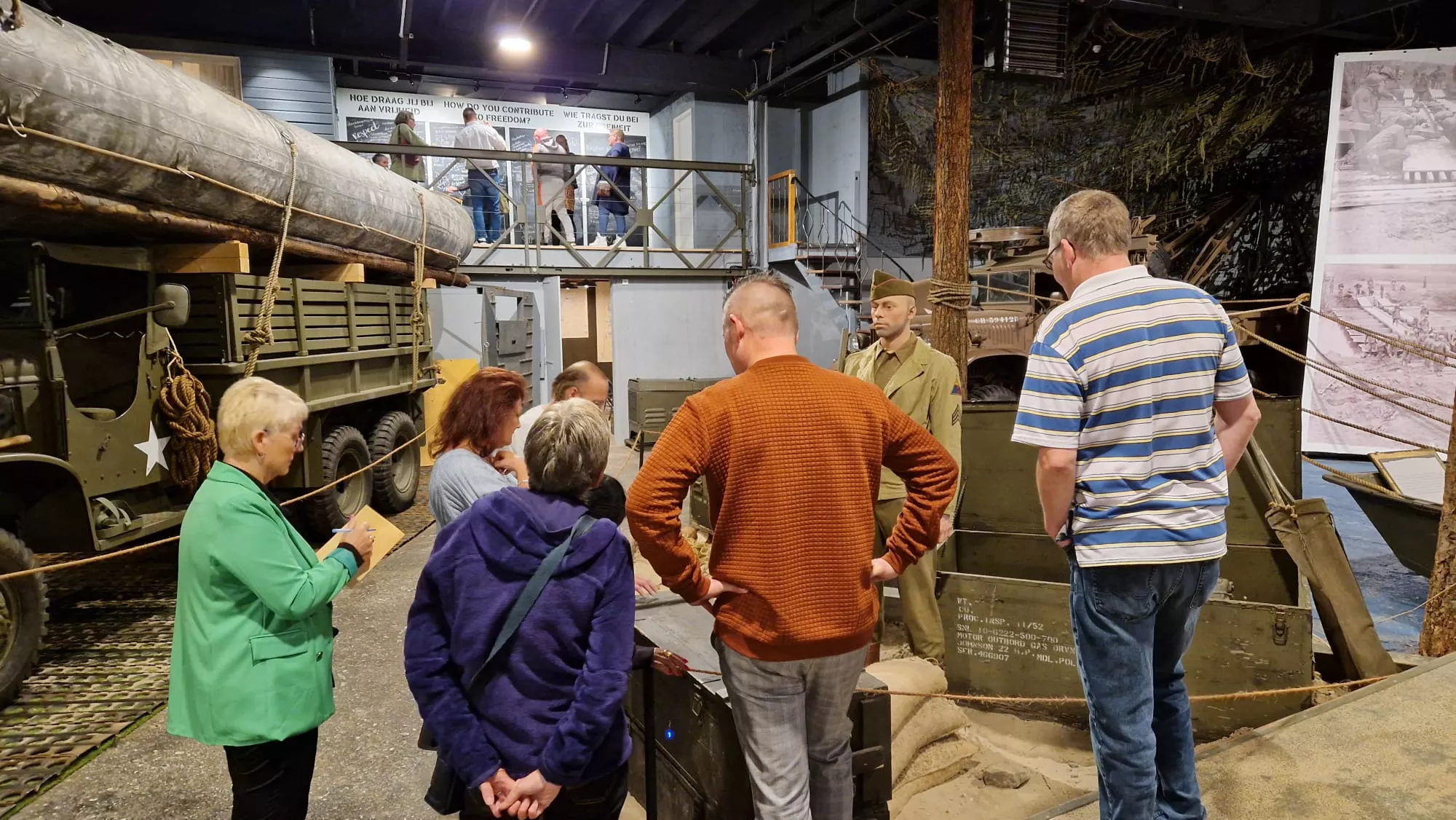 Mensen bezoeken een militair legermuseum en kijken naar legervoertuigen, motoren, boten, tanks, kanonnen en wapens