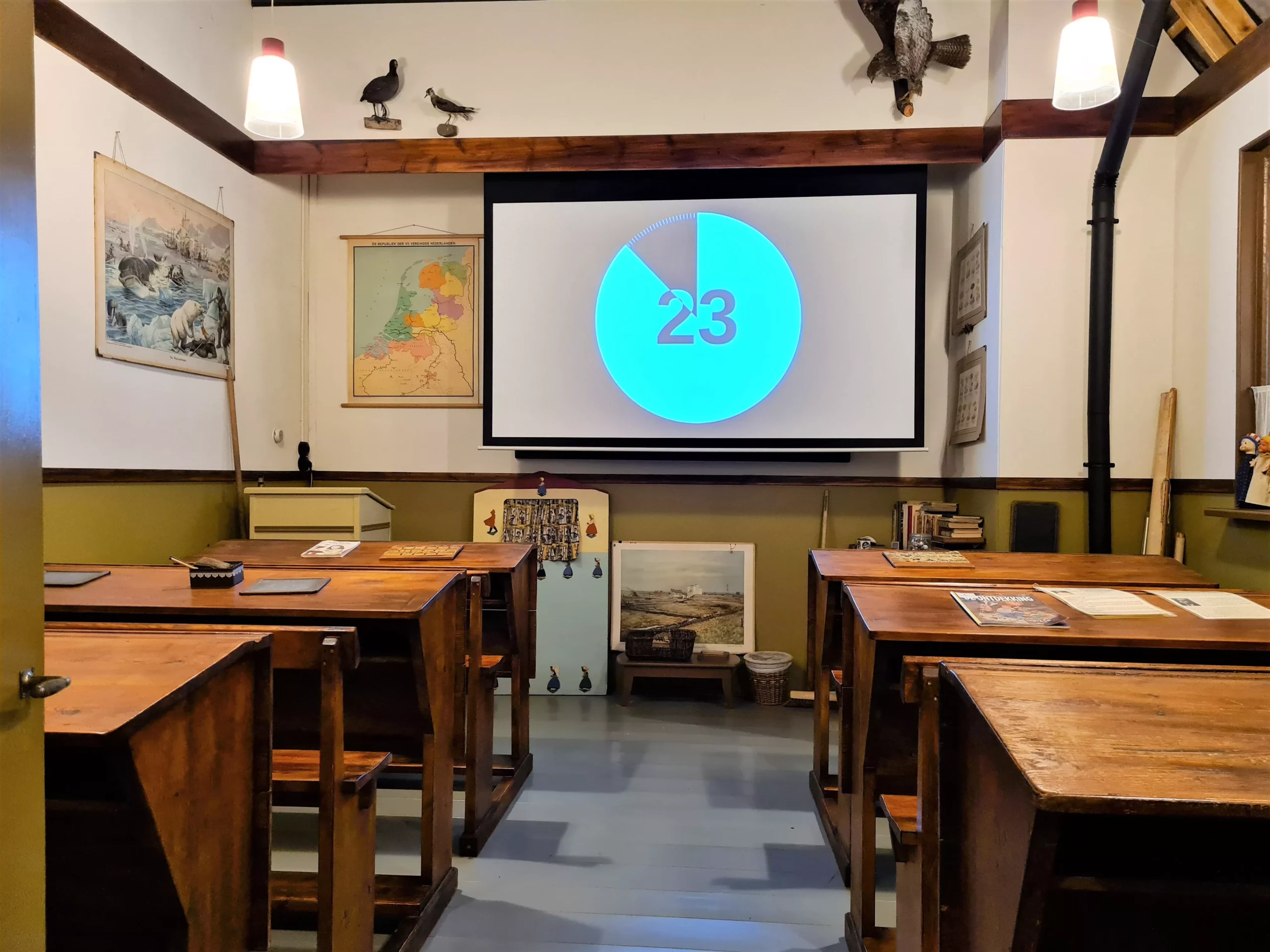 Oud klaslokaaltje in een museum met schoolbanken, oude landkaarten, opgezette dieren, schoolbord