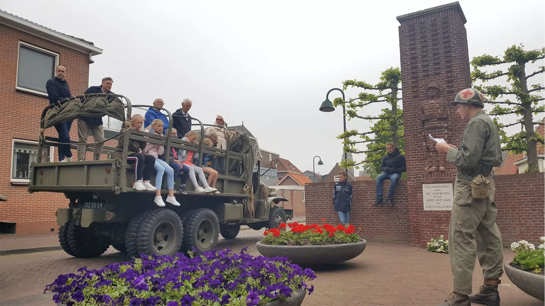 Schoolkinderen zitten tijdens een leuke schoolexcursie in een legerauto en rijden een rondrit waarbij ze verhalen over W.O.II Monumenten horen